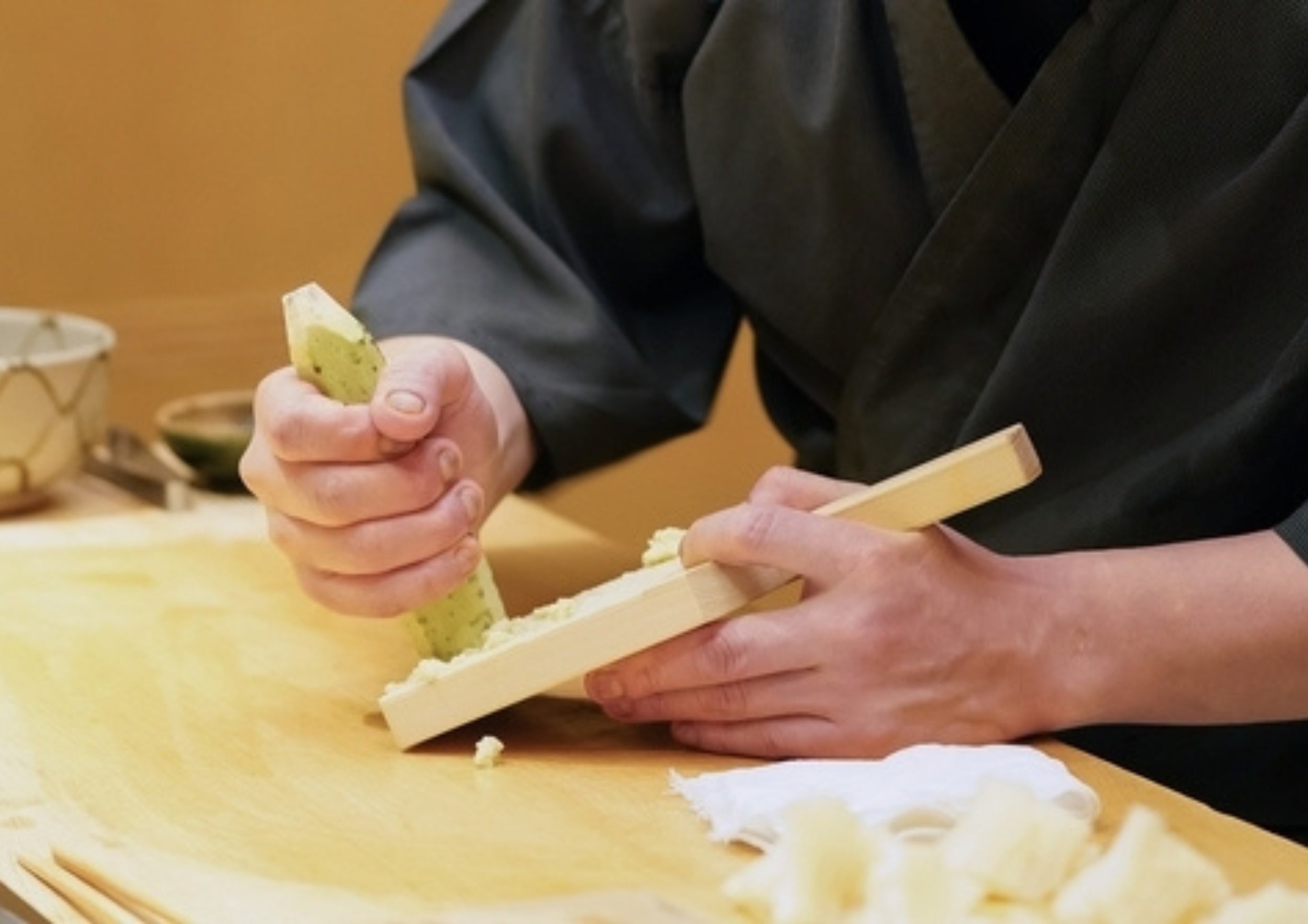 Chef grinding fresh wasabi on a wooden grater